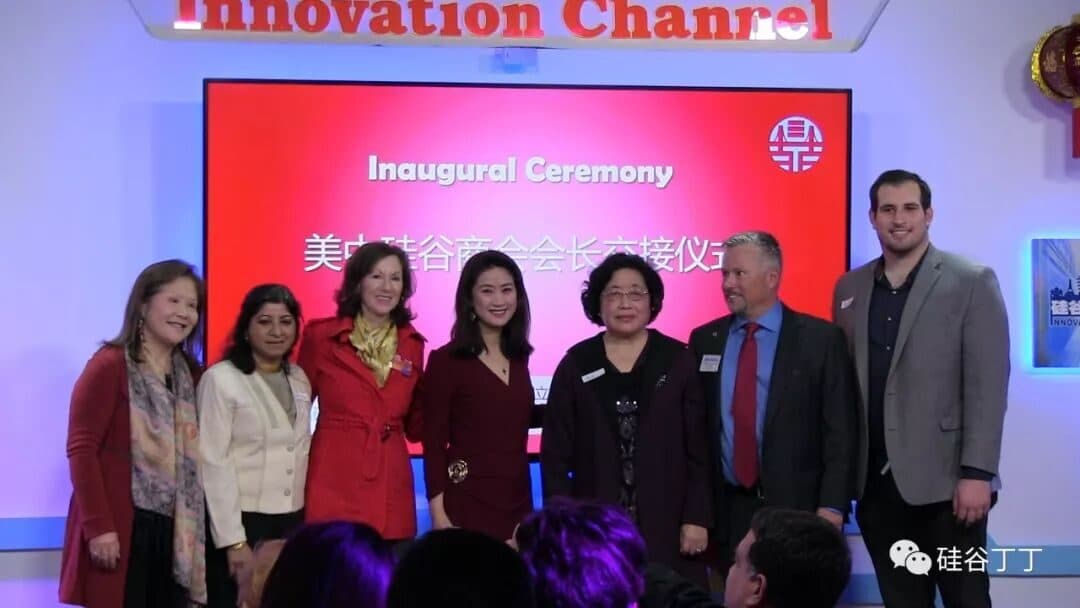 七位与会者站在写有"Inaugural Ceremony 美中硅谷商会会长交接仪式"的大屏幕前,演播厅内挂着红灯笼。